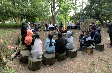 A group of pupils from Greenbank Primary School are set around a camp fire