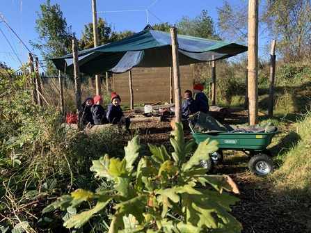 Pupils sat under a shelter in a green school grounds